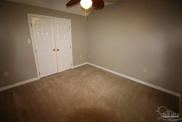 a view of an empty room and chandelier fan