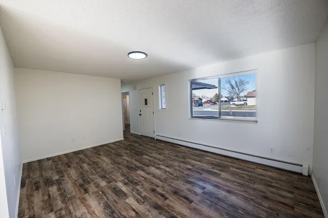 an empty room with wooden floor and window