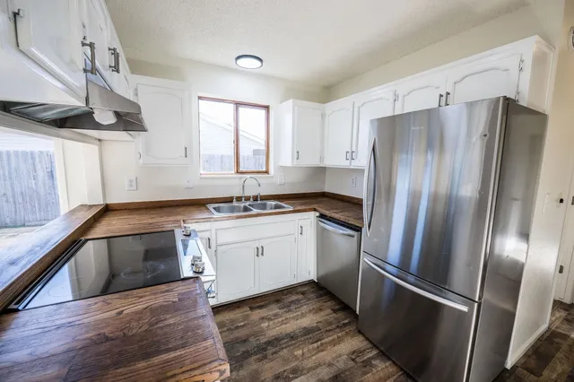 a kitchen with granite countertop a stove a sink and a refrigerator