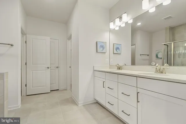 a bathroom with double vanity sink a vanity and a large mirror
