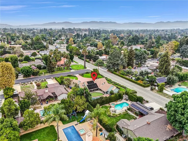 an aerial view of residential houses with outdoor space and trees