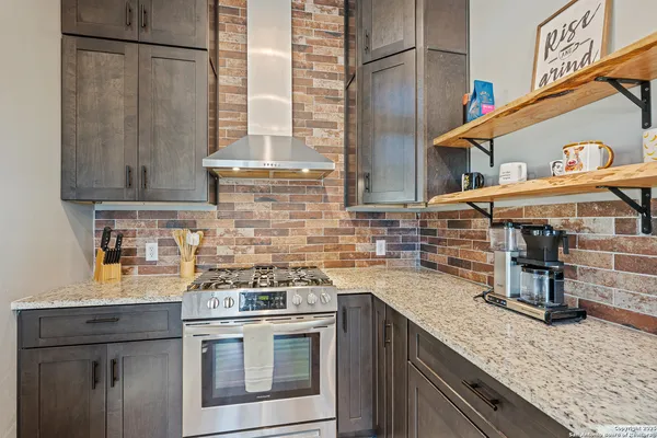 a kitchen with stainless steel appliances granite countertop a kitchen island a stove a refrigerator and cabinets