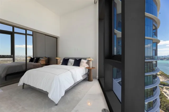 a bedroom with a bed lamp and a large window