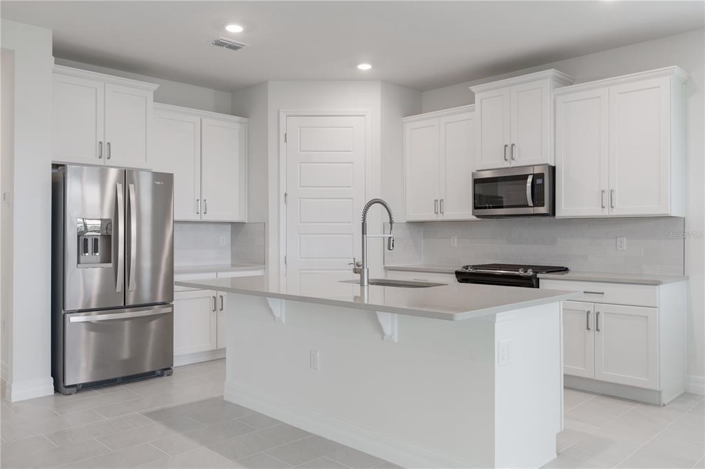 3944 Kennebunk Loop Mount Dora, FL 32757 - Photo 11 of 32 a kitchen with stainless steel appliances granite countertop a refrigerator a stove a sink and white cabinets