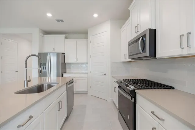 a view of a kitchen with refrigerator and white cabinets