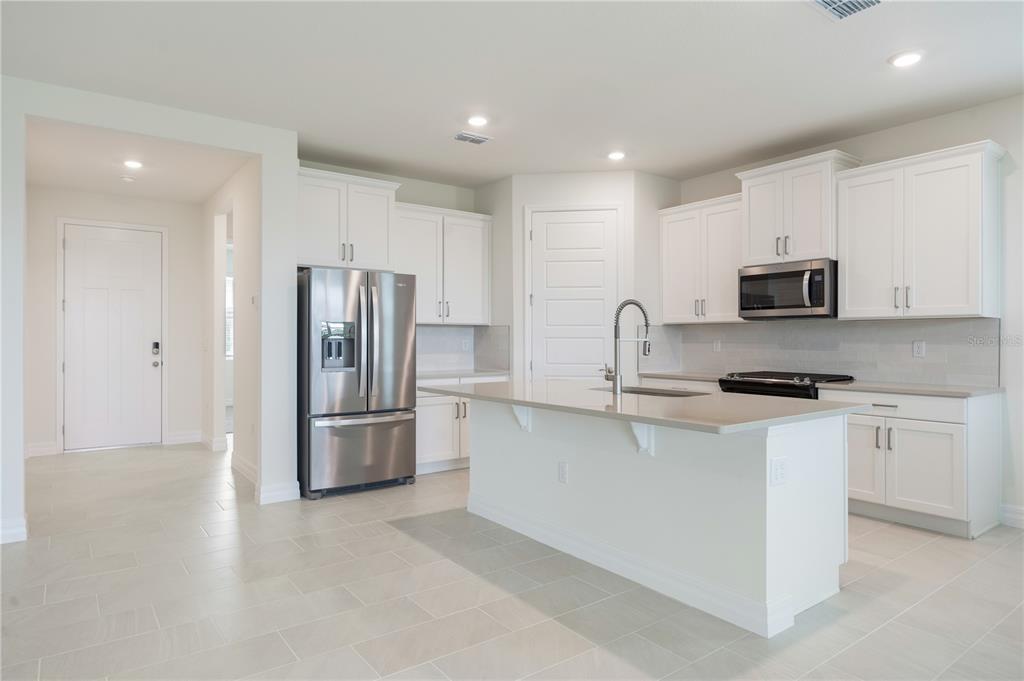 3944 Kennebunk Loop Mount Dora, FL 32757 - Photo 10 of 32 a kitchen with stainless steel appliances granite countertop a refrigerator a stove a sink and a microwave