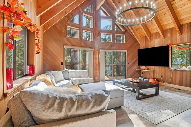 a living room with furniture a flat screen tv and a floor to ceiling window