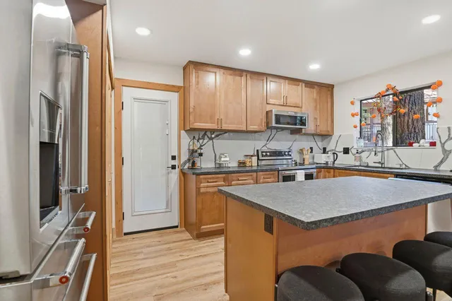 a kitchen with stainless steel appliances granite countertop a refrigerator a stove and a sink with wooden floor
