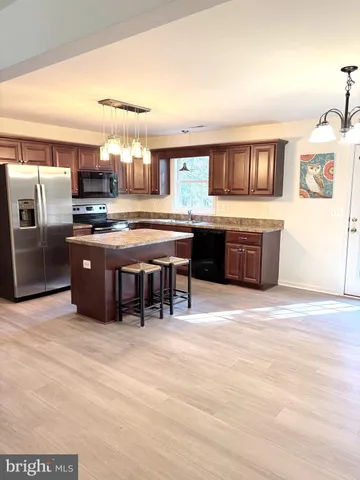 a kitchen with stainless steel appliances granite countertop a refrigerator a stove a sink a dining table and chairs with wooden floor