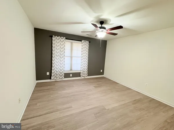 an empty room with windows and fan