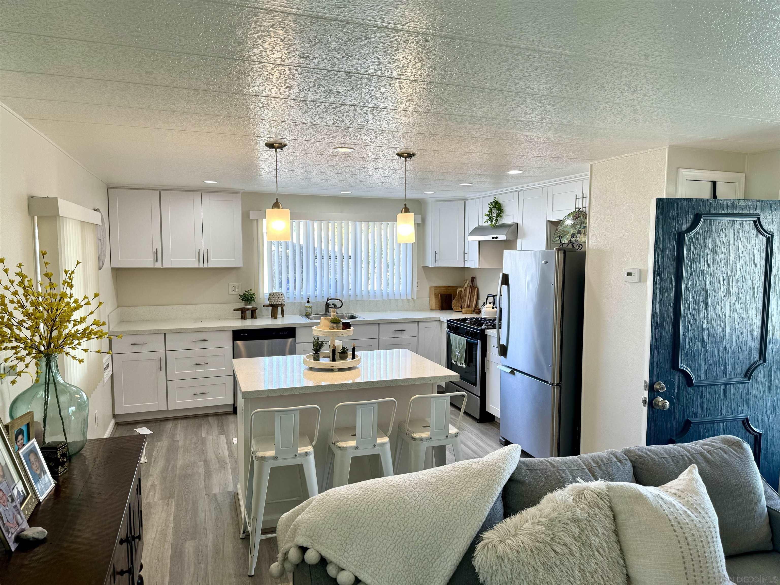 a large kitchen with stainless steel appliances kitchen island granite countertop a refrigerator a stove a sink dishwasher with a dining table and chairs with wooden floor