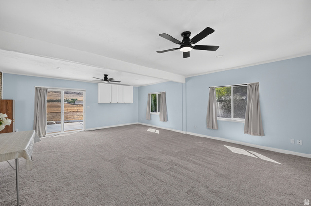 4468 North Droubay Road Tooele, UT 84074 - Photo 17 of 60 Spacious room featuring light blue walls, gray carpet flooring, dual ceiling fans, and multiple windows