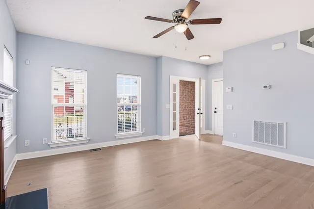 a view of an empty room with a window and wooden floor