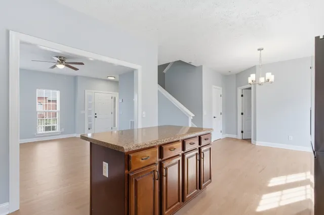 a kitchen with stainless steel appliances granite countertop a stove top oven a sink dishwasher and a refrigerator with wooden floor