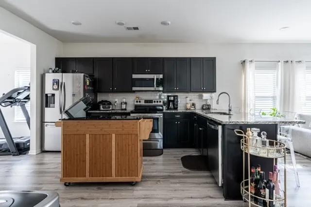 a kitchen with stainless steel appliances granite countertop a refrigerator a stove top oven a sink and dishwasher