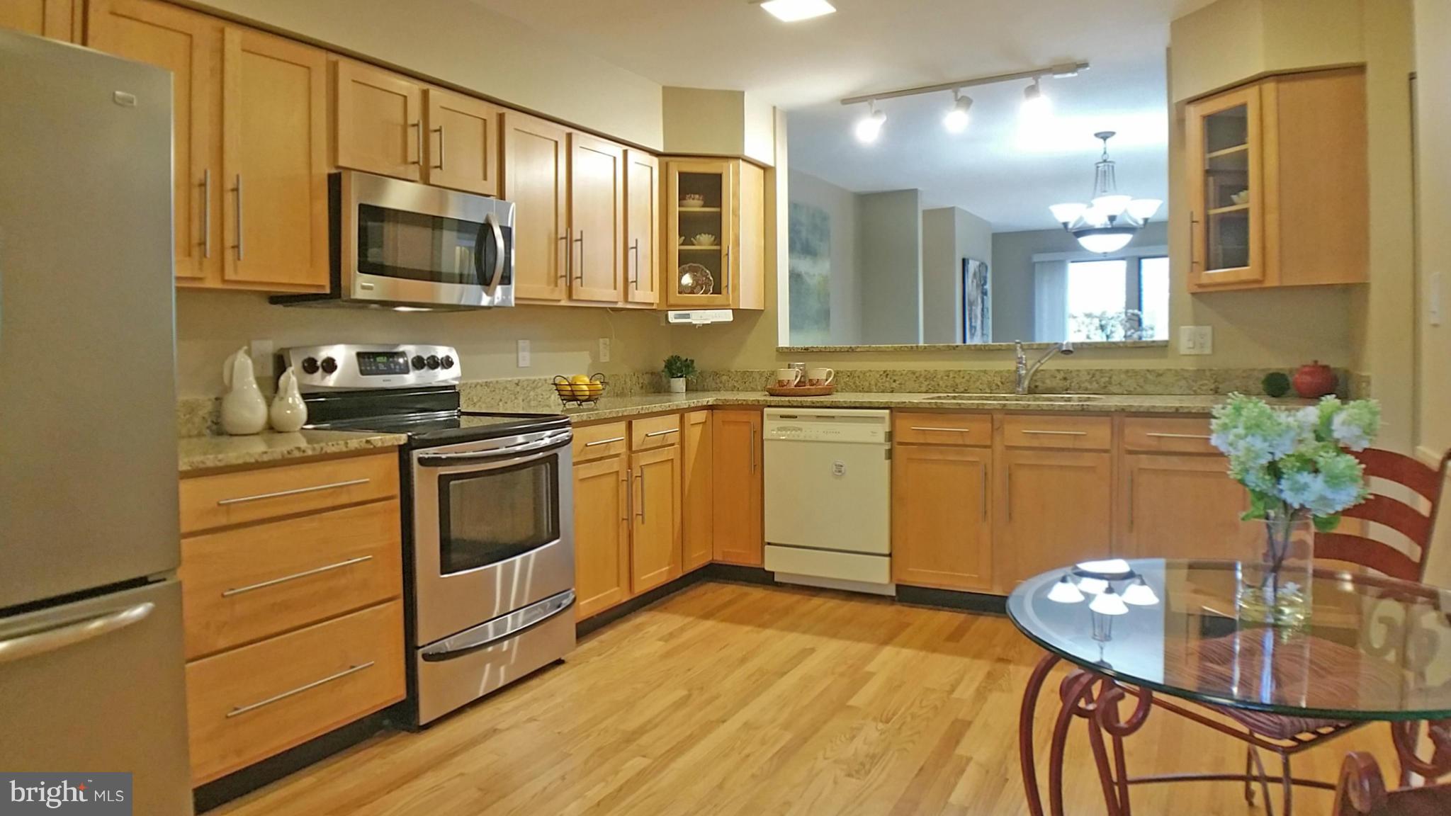 11204 Lagoon Lane Reston, VA 20191 - Photo 7 of 30 a kitchen with stainless steel appliances a stove a sink cabinets and a wooden floor