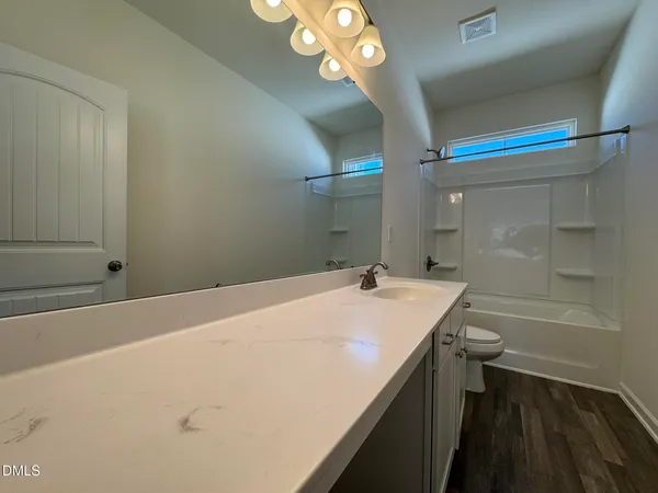 a bathroom with a granite countertop sink a toilet and shower
