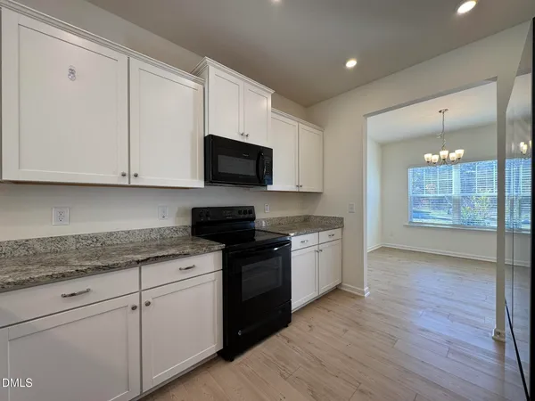 a kitchen with stainless steel appliances granite countertop a stove a sink and white cabinets