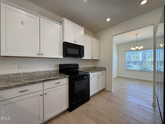 a kitchen with stainless steel appliances granite countertop a stove a sink and white cabinets
