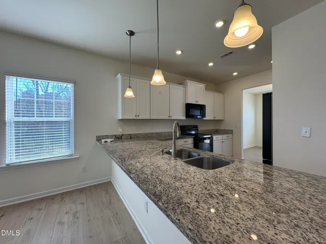 a kitchen with stainless steel appliances granite countertop a sink a stove and a wooden floors