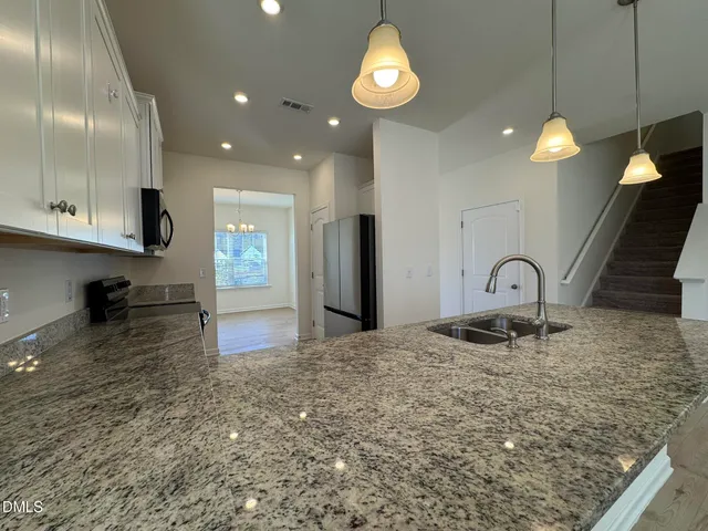 a kitchen with stainless steel appliances granite countertop a sink a stove and a refrigerator