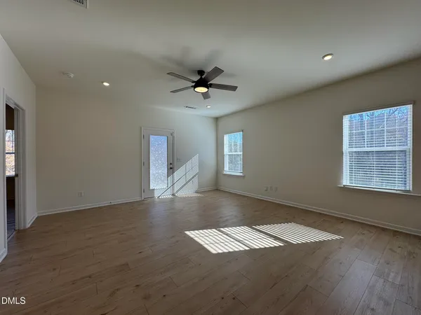 an empty room with wooden floor and windows