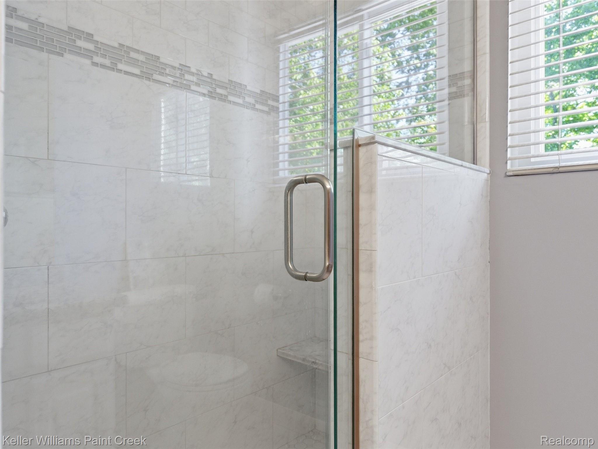2842 Manorwood Road Troy, MI 48085 - Photo 56 of 72 Glass-enclosed shower featuring white tile walls, a decorative mosaic tile accent stripe, and a built-in shower bench