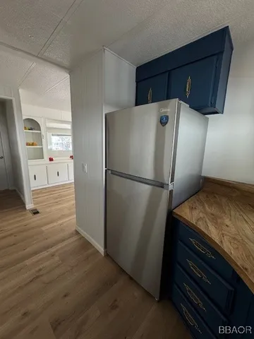 a kitchen with a refrigerator and a wooden floor