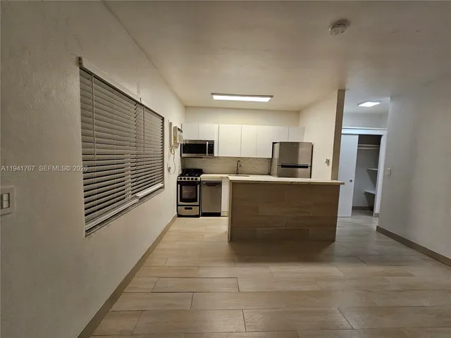 a kitchen with stainless steel appliances kitchen island granite countertop a refrigerator oven a sink a stove with wooden floors