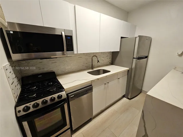 a kitchen with stainless steel appliances a stove a microwave and a sink