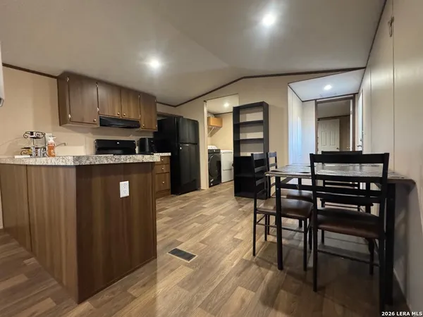 a kitchen with stainless steel appliances granite countertop a stove top oven a sink dishwasher a dining table and chairs with wooden floor