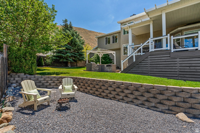 14883 Tooele Lane Draper, UT 84020 - Photo 6 of 49 Tiered backyard featuring a gravel seating area, a retaining wall, and a manicured lawn