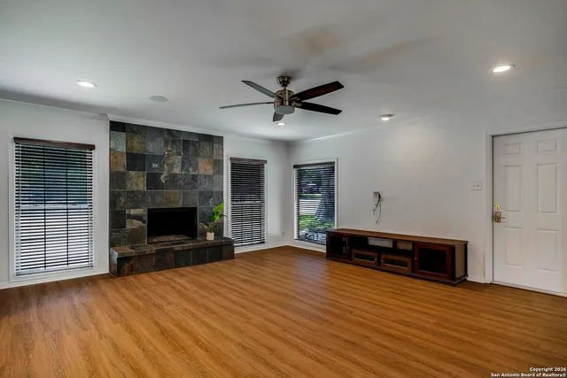 an empty room with wooden floor a fireplace and window