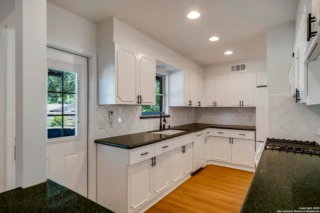 a kitchen with granite countertop a sink stove and cabinets
