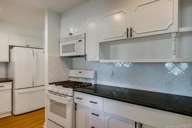a kitchen with granite countertop white cabinets and white appliances