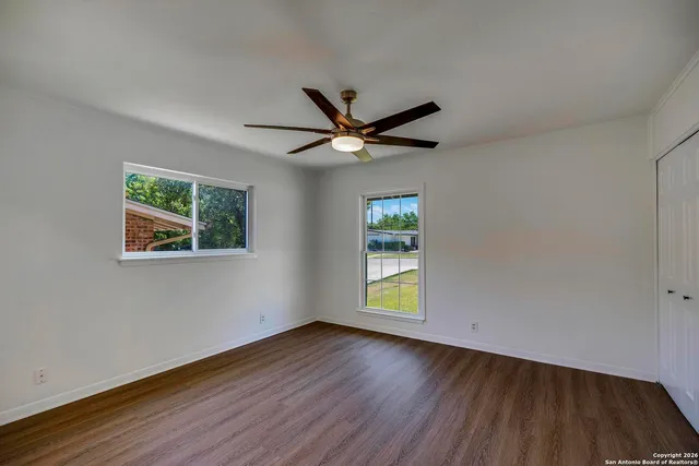 an empty room with wooden floor and windows