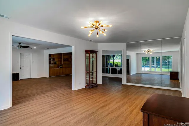 a view of an empty room with window and wooden floor