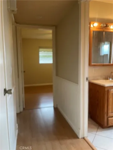 a view of a hallway with wooden floor and a bathroom