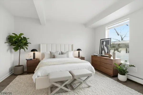 a bedroom with a bed table flowerpot and window