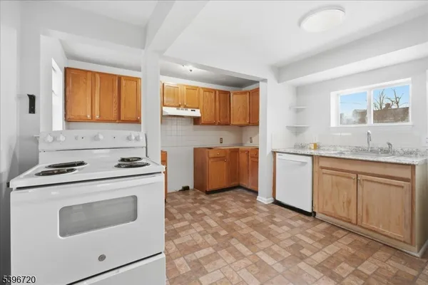 a kitchen with granite countertop a sink stove top oven and cabinets