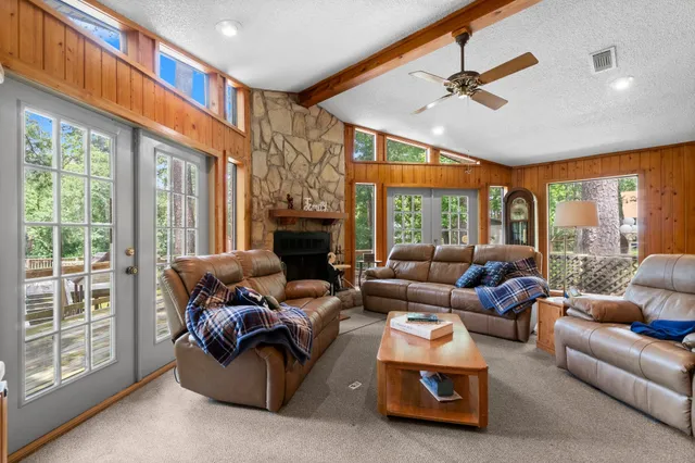 a living room with furniture a ceiling fan and a floor to ceiling window