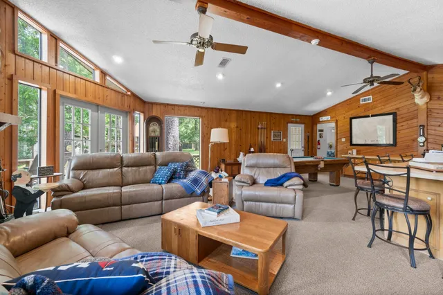 a living room with furniture a ceiling fan and a large window