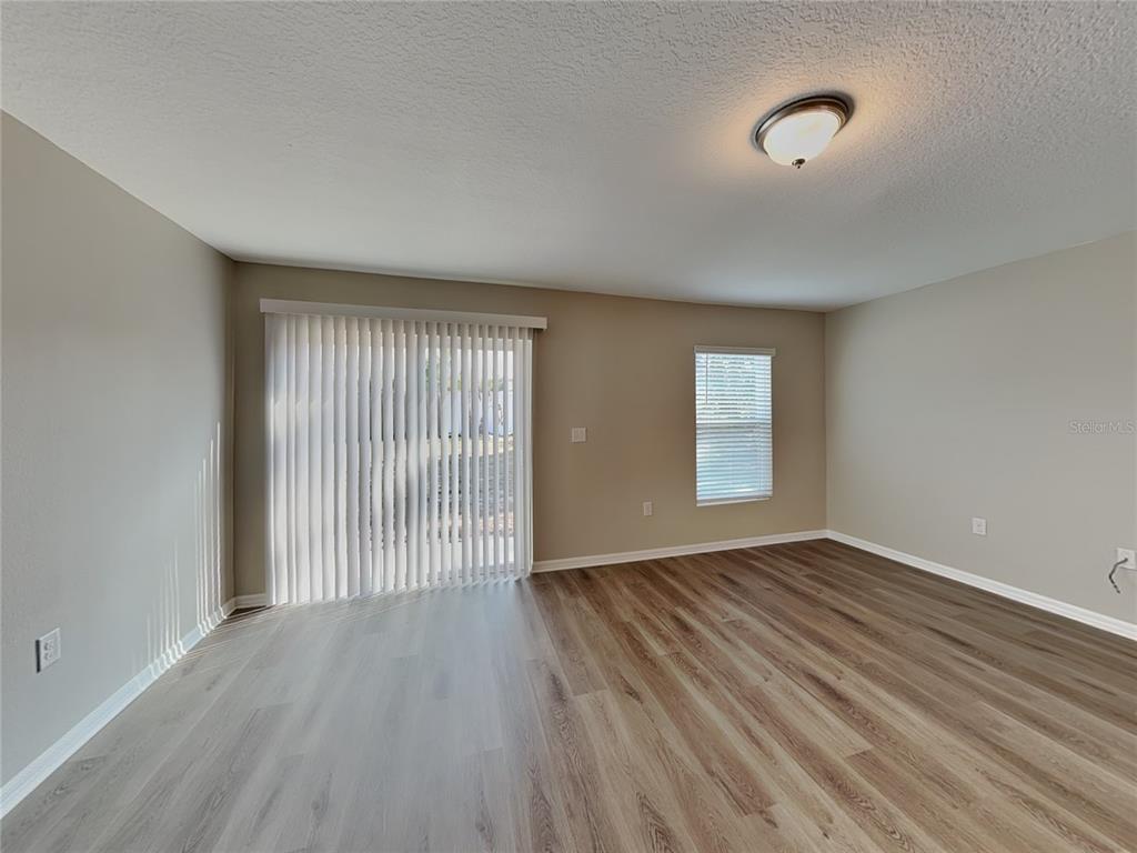 Undisclosed Address Spring Hill, FL 34608 - Photo 2 of 17 an empty room with wooden floor and windows