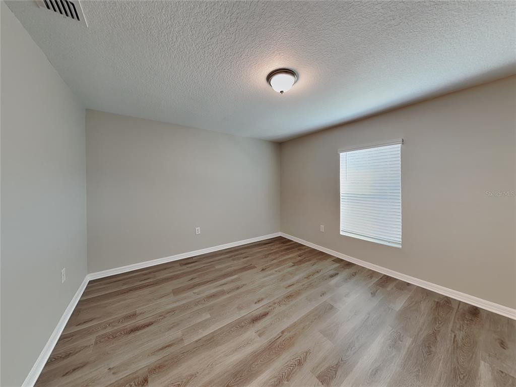 Undisclosed Address Spring Hill, FL 34608 - Photo 5 of 17 a view of an empty room with wooden floor and a window