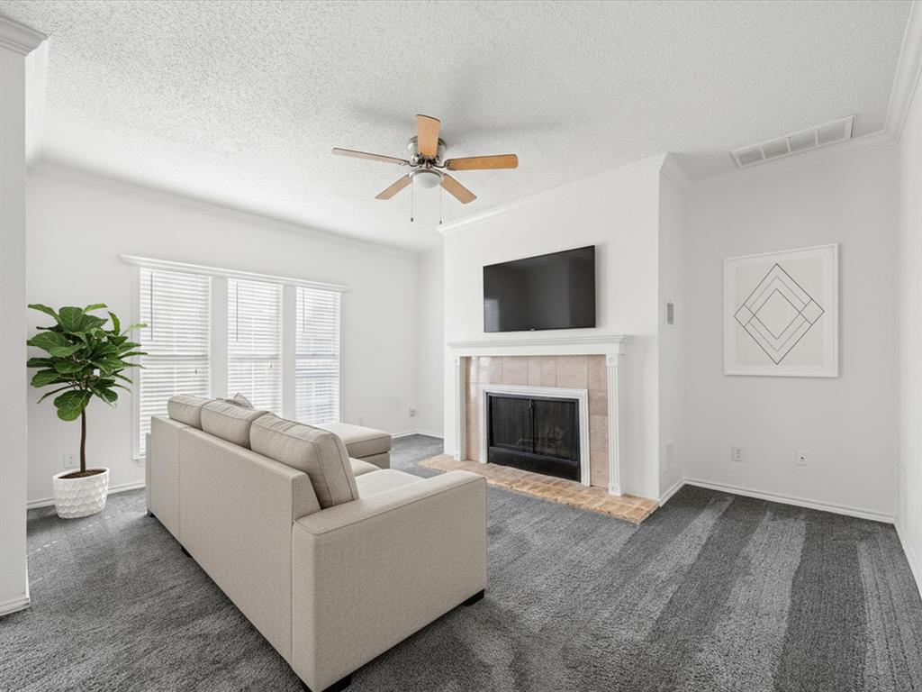 5310 Keller Springs Road, Unit 332 Dallas, TX 75248 - Photo 3 of 39 Living area featuring a tile fireplace, a textured ceiling, dark colored carpet, a ceiling fan, and ornamental molding