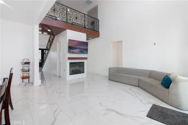 a living room with stainless steel appliances furniture a rug and a kitchen view