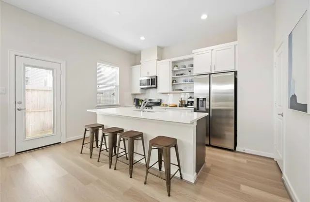 a kitchen with stainless steel appliances a dining table chairs refrigerator and sink
