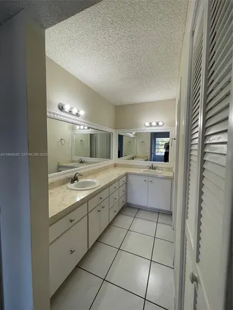 a large white bathroom with a double vanity sink a mirror and a shower