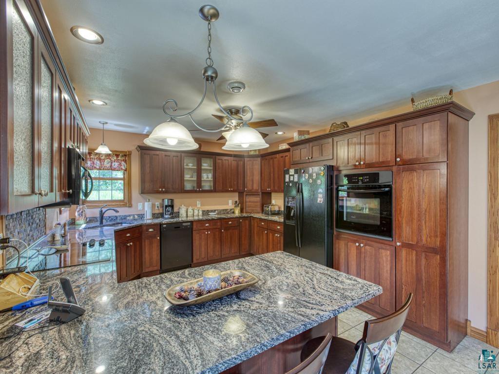 4678 Ridgeview Drive Superior, WI 54880 - Photo 3 of 43 Kitchen with pendant lighting, black appliances, stone countertops, and kitchen peninsula