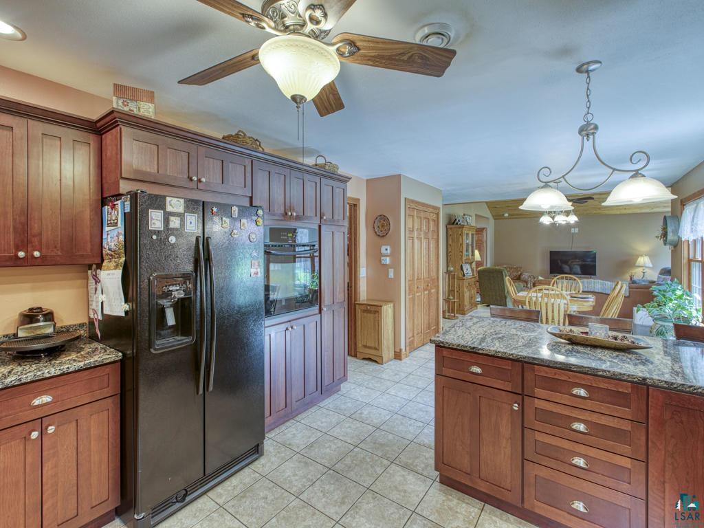4678 Ridgeview Drive Superior, WI 54880 - Photo 6 of 43 Kitchen with black appliances, hanging light fixtures, light tile patterned floors, dark stone countertops, and ceiling fan